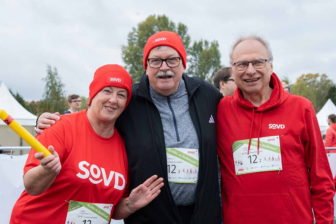 Drei Personen halten einen Staffelstab. 